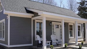 A single-story house with a covered porch, two white chairs, and a small table. - The Cottage At Hershey Lane Farm (Frenchtown)