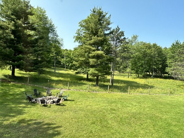 A grassy outdoor area with a picnic table and chairs, surrounded by trees and a fence. - Alvie House: 5 min from Wisp&DCL, Outdoor Fire Pit, Fireplaces, Country Kitchen (Accident)