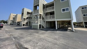 A multi-story building with a central staircase, balconies, and a parking area. - Sea Turtle Sanctuary-Ocean Front Condo on Perfect Private Beach!  (Oak Island)