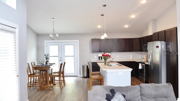 A modern kitchen with dark wooden cabinets, a stainless steel refrigerator, and a central island with a sink. - Modern home near downtown Hendersonville (Hendersonville)
