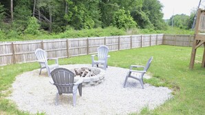 A backyard with a fire pit and four Adirondack chairs arranged around it. - Modern home near downtown Hendersonville (Hendersonville)