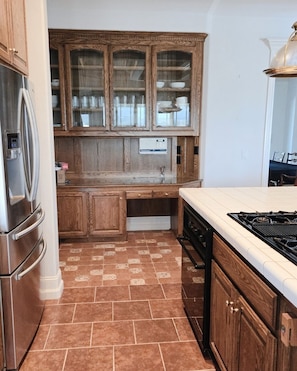 Kitchen features a gas stove, wooden cabinets, and a stainless steel refrigerator.