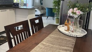 Un comedor con una mesa de madera, sillas y una bandeja con una botella y copas.