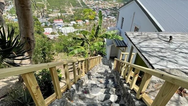 Una escalera de piedra con barandillas de madera que conduce a un edificio con techo de metal.