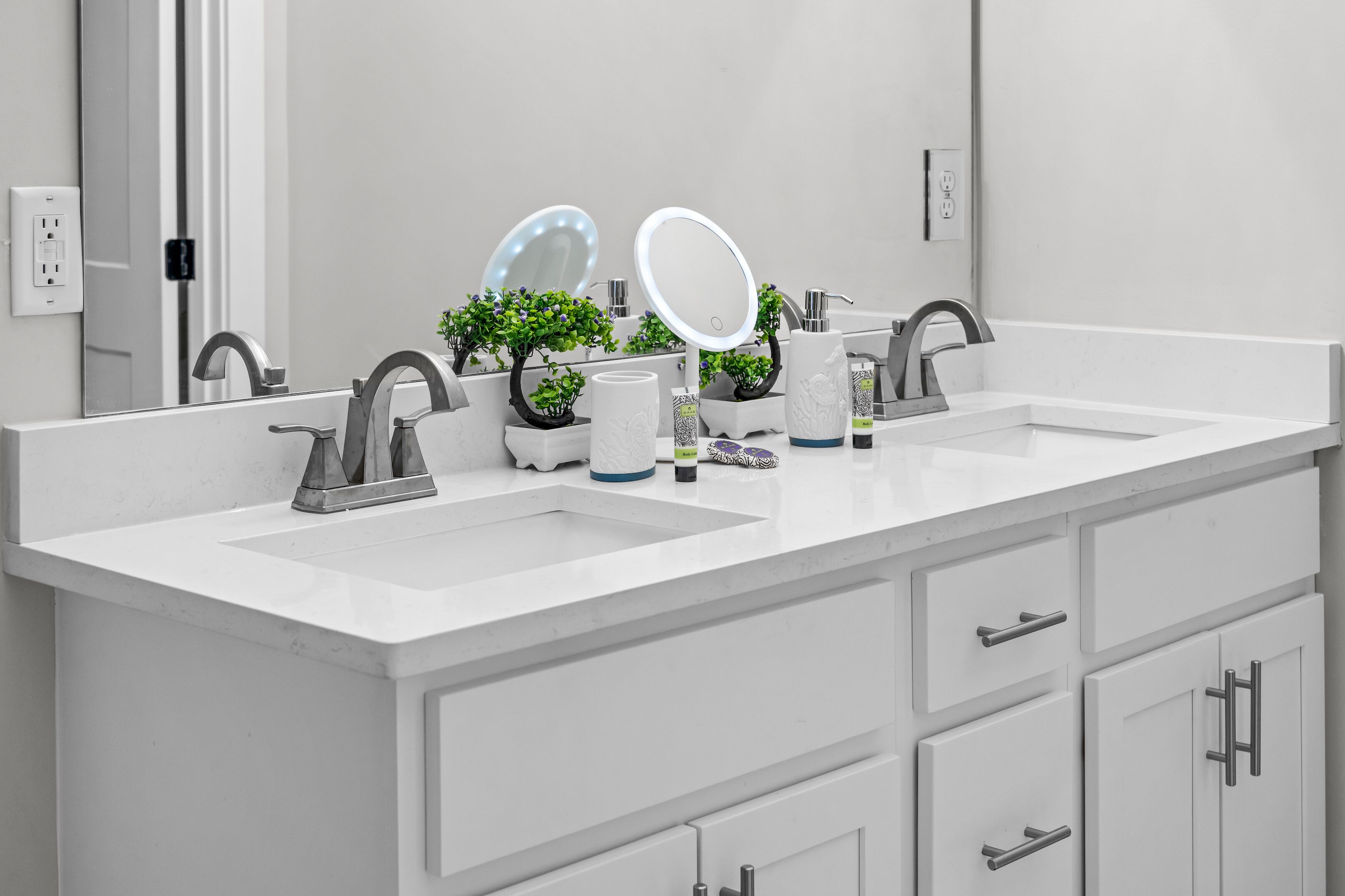 A modern bathroom with two sinks, a large mirror, and a cabinet with drawers.