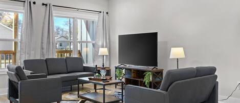 Een moderne woonkamer met een modulaire bank, een salontafel en een televisie.