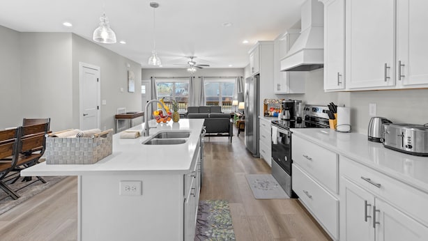 A modern kitchen with white cabinetry, a central island, and a dining area with a bench. - NEW Four Bedroom Nashville Downtown house to enjoy 2 mins to Broadway. (Nashville)