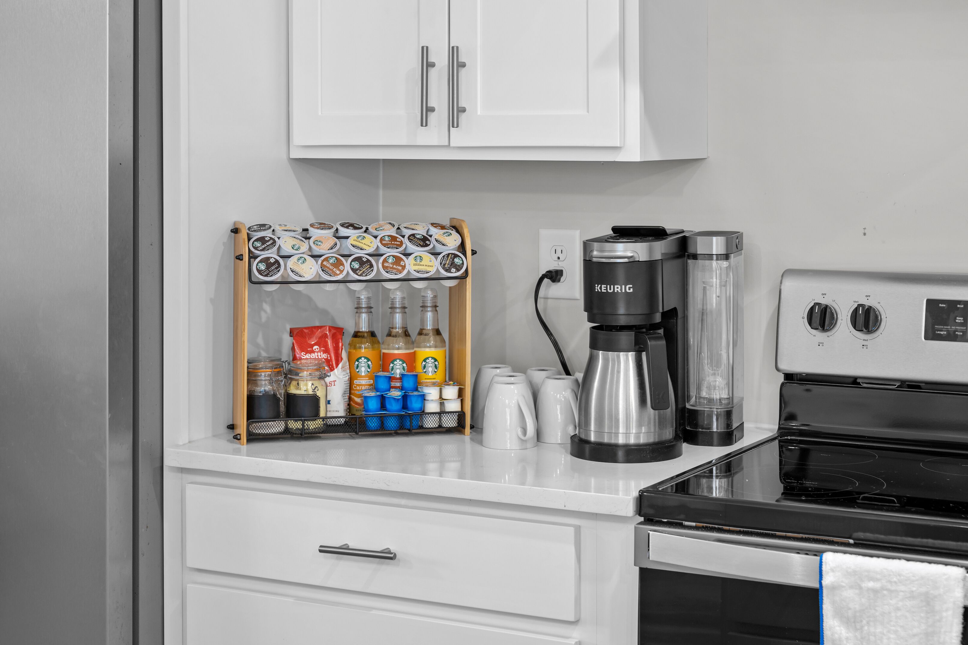 Een keuken met een koffiezetapparaat, waterkoker en een koffiemolen op het aanrecht.