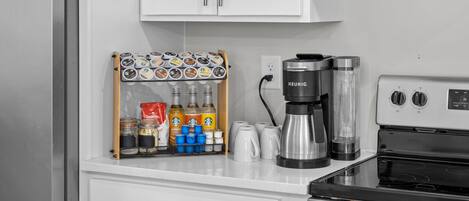 Una cocina con cafetera, hervidor y molinillo de café sobre la encimera.