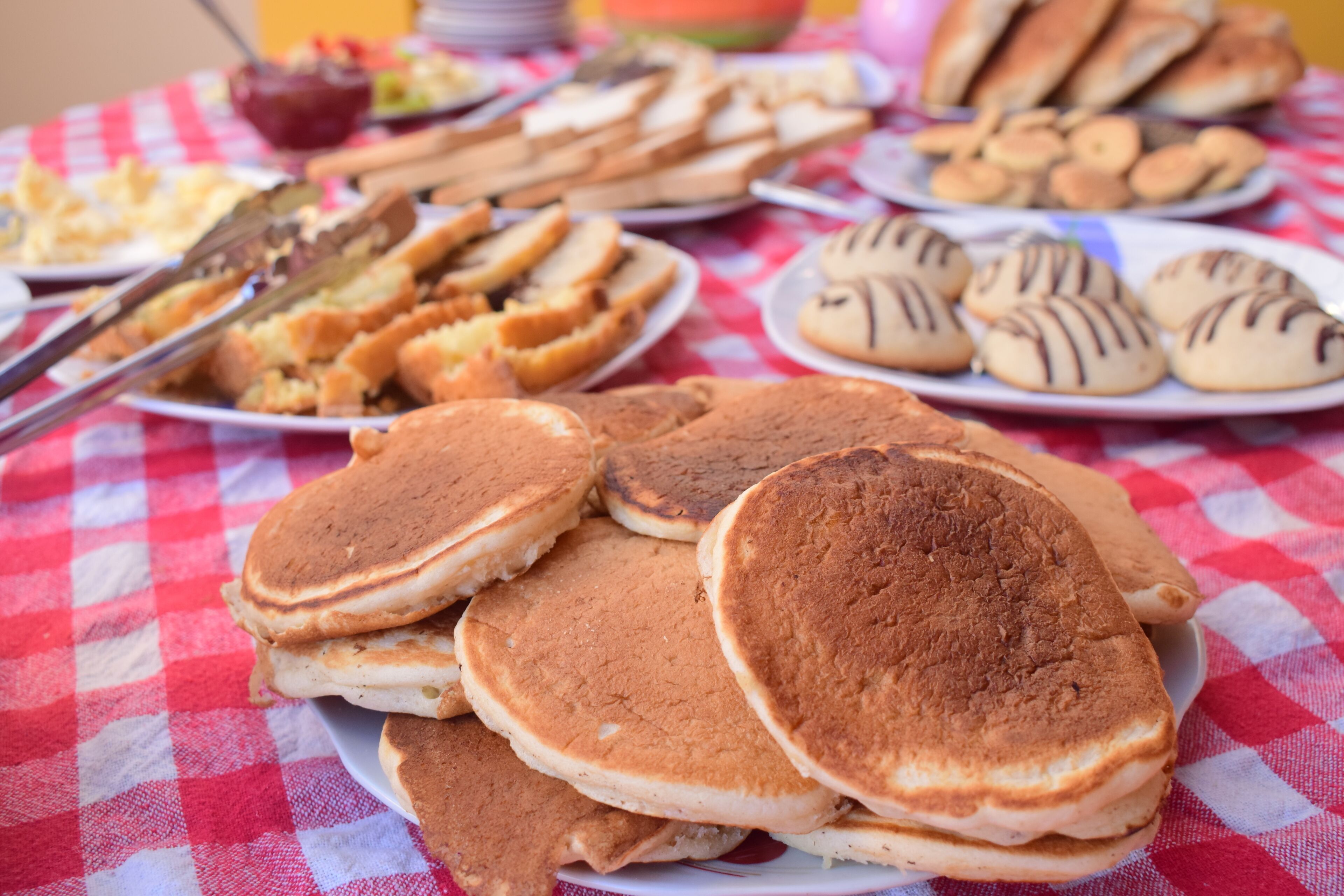 A table with various breakfast items including pancakes, biscuits, and bread.