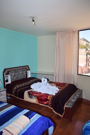 A hotel room with a bed, a bench, a window with curtains, and a view of buildings. - Skylake (Copacabana)