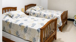 Een slaapkamer met twee houten bedden, een hanglamp en kunstwerken aan de wanden.