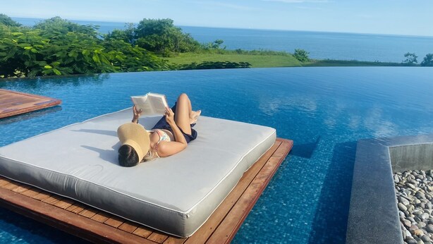 A person relaxing on a floating platform in a pool with a view of the ocean. - Front Beach Charming Zen Apartment (San Carlos)