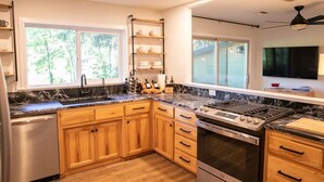 Une cuisine moderne avec des meubles en bois, un lave-vaisselle en acier inoxydable, un four encastré et une cuisinière à gaz.