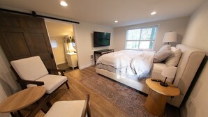 Une chambre à coucher avec un lit, une télévision, un canapé, une chaise et une petite table.
