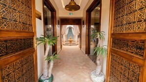 A hallway with ornate wooden doors, a tiled floor, and potted plants. - Le Palais Averroes - Adults Only (Marrakech)