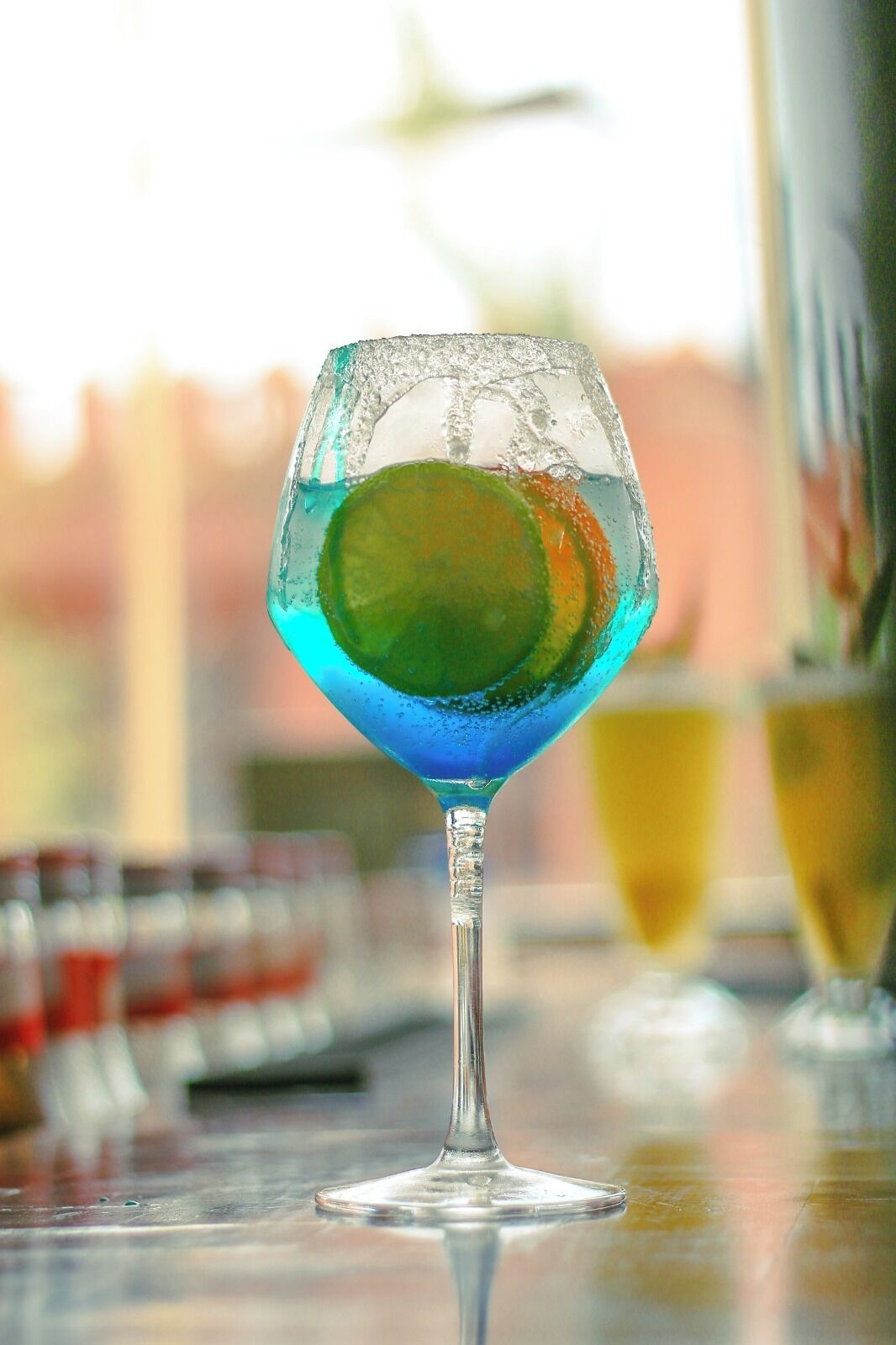 Een cocktailglas met een limoenpartje op een bargedeelte.