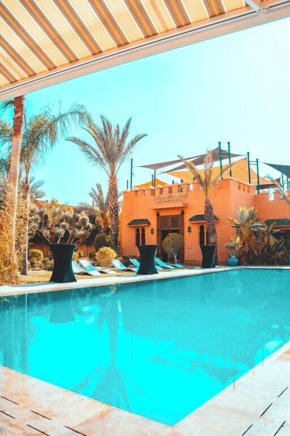 Una piscina al aire libre, sombrillas, sillones reclinables de piscina