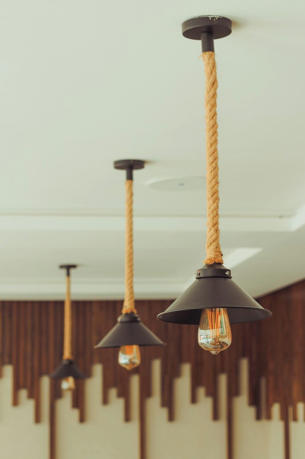 A ceiling with three pendant lights featuring black shades and exposed bulbs.