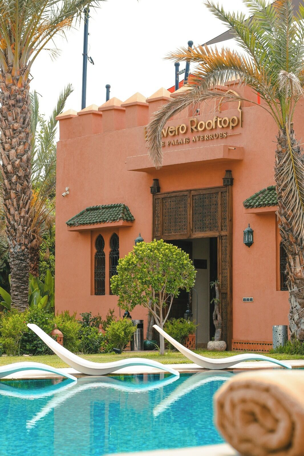 A building with a sign reading "Alver Rootoop" and a pool area in front.