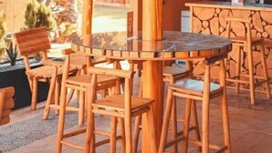 An outdoor seating area with wooden tables and chairs, a thatched roof, and a stone wall in the background. - Le Palais Averroes - Adults Only (Marrakech)