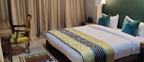 Una habitación de hotel con cama, una silla, una mesita de noche y una ventana con cortinas.