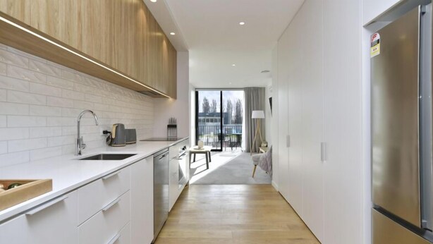 A modern kitchen with white cabinetry, a stainless steel refrigerator, and a view to the outside through a glass door. - Worcester Terrace One -Top inner city location (Christchurch)