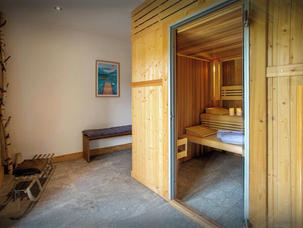 A wooden sauna room with benches and a bench outside.