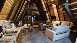 Un salón estilo ático con techo alto, vigas de madera, encimera de mármol y mobiliario moderno.