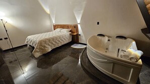Un dormitorio con cama, cabecero de madera, mesita de noche y bañera con toallas.