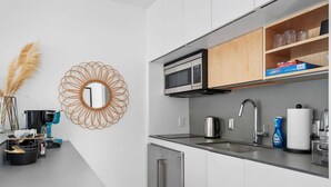 Una cocina moderna con electrodomésticos de acero inoxidable, microondas integrado y cafetera.