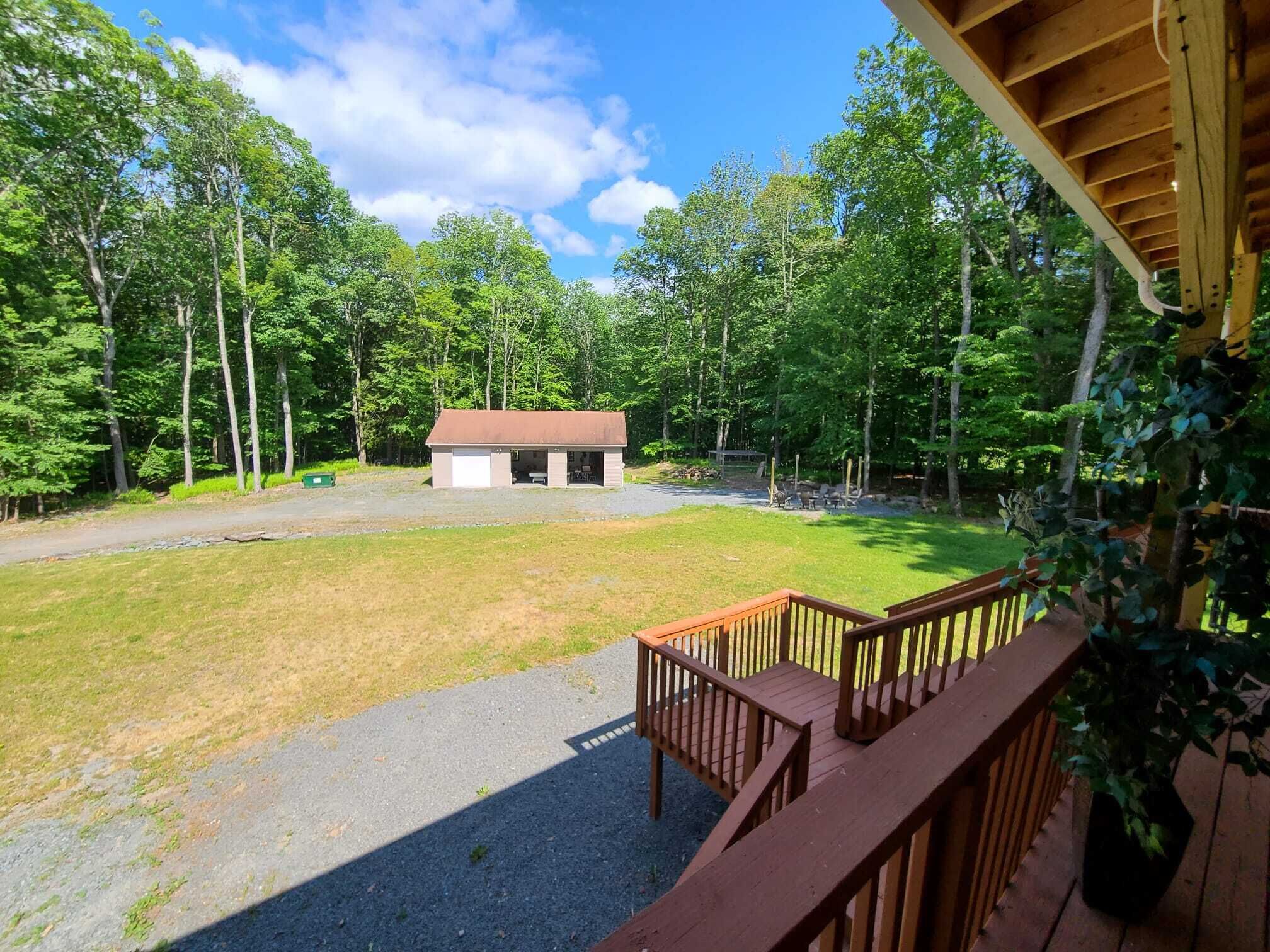 A cabin with a gravel driveway, surrounded by a forest.