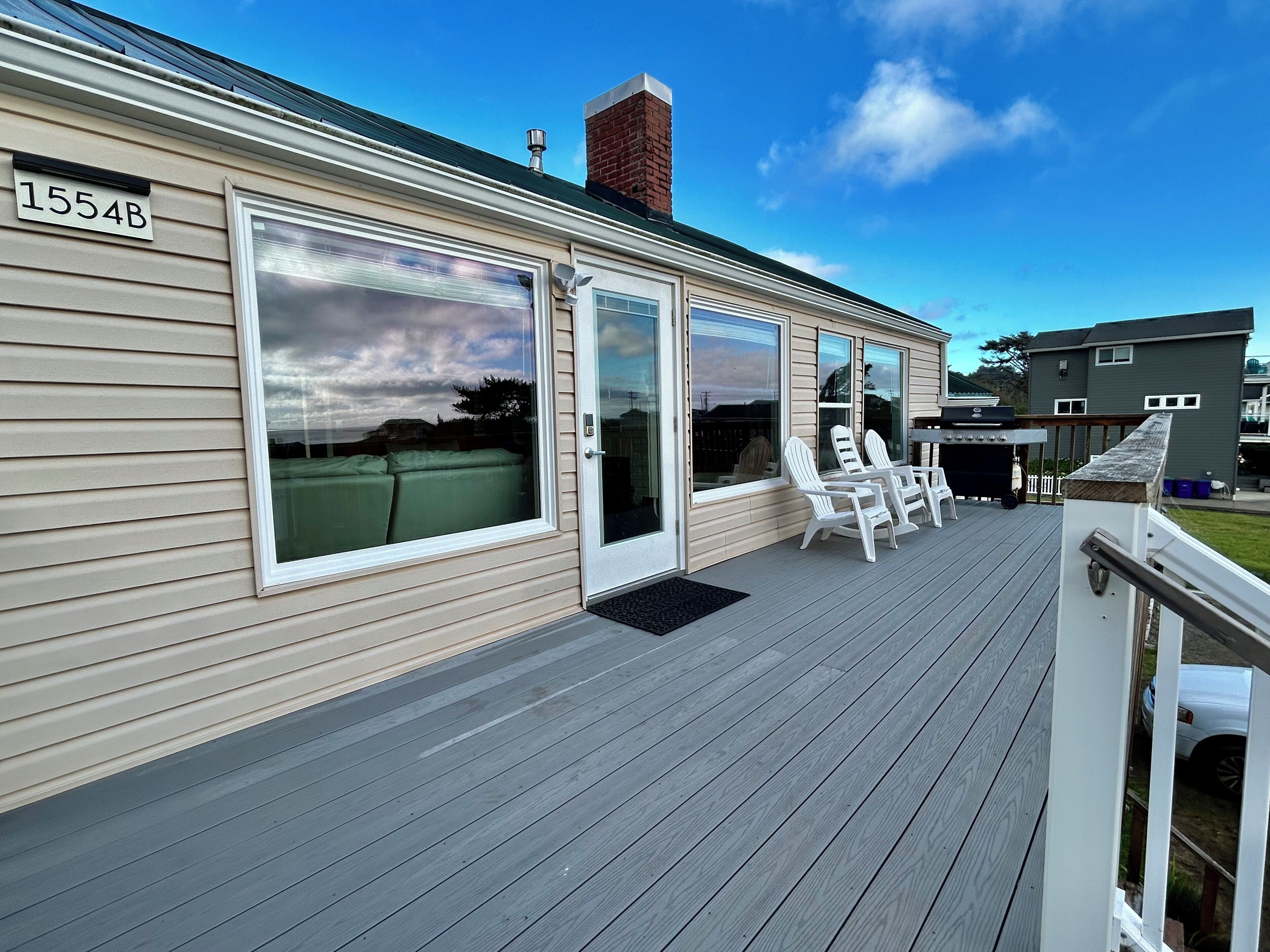 A house with a deck, sliding glass doors, and a number '1554B' sign.
