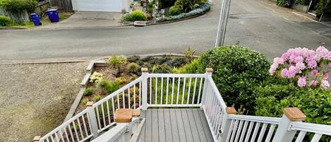 A wooden deck with white railings leading to a house with a garage.
