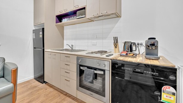 Una cocina compacta equipada con refrigerador, estufa, horno, lavavajillas y cafetera.