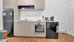 Una cocina compacta con refrigerador, horno, lavavajillas y microondas en la encimera.