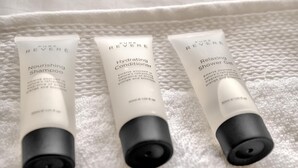 Trois bouteilles de produits de la marque Pure Reveré, posées sur une surface blanche texturée.
