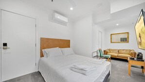Une chambre d’hôtel moderne avec un grand lit, un canapé, une télévision et un tableau au mur.