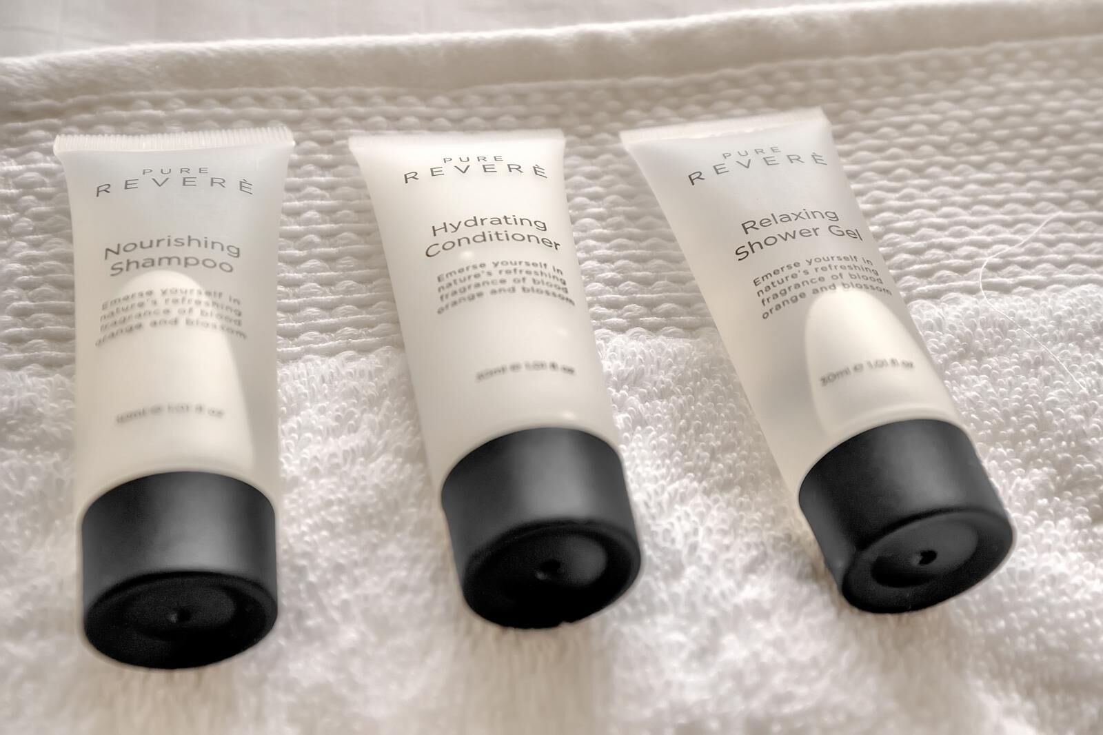Three bottles of Pure Reveré products on a white textured surface.