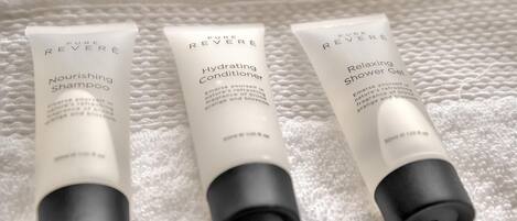 Three bottles of Pure Reveré products on a white textured surface.