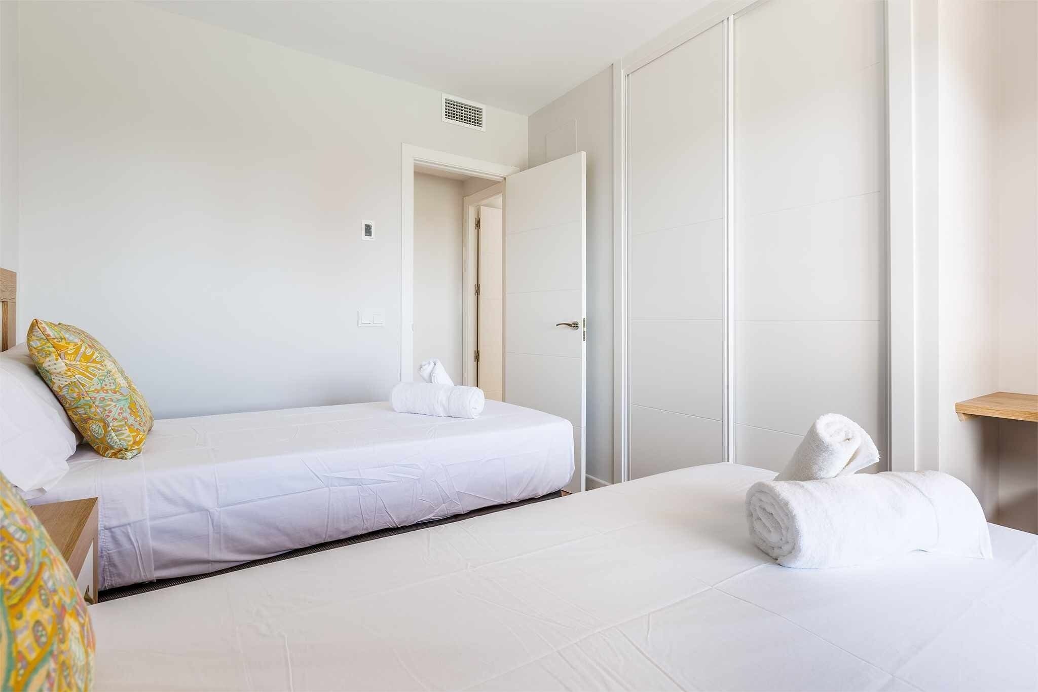 Habitación de hotel con cama, mesita de noche, toalla y puerta.