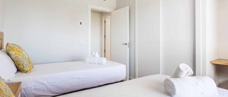 Habitación de hotel con cama, mesita de noche, toalla y puerta.