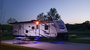 A large RV with a covered patio area, a table, and a bench. - ONSITE 2019 RV, Camping, South Haven, MI (South Haven)