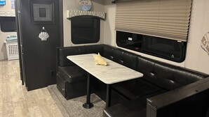 A compact RV kitchen with a black countertop, a small table, and a built-in oven. - ONSITE 2019 RV, Camping, South Haven, MI (South Haven)