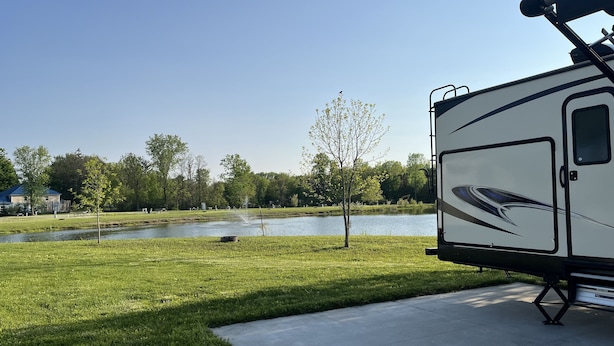 A recreational vehicle parked near a lake with a grassy area and a building in the background. - ONSITE 2019 RV, Camping, South Haven, MI (South Haven)