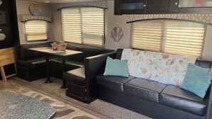 A compact RV interior with a dining area, seating, and a television. - ONSITE 2019 RV, Camping, South Haven, MI (South Haven)