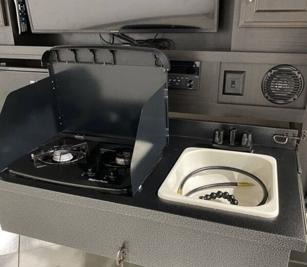 Cocina compacta con estufa a gas, un lavabo y una pequeña encimera.