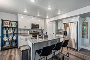 Enjoy cooking in this well-equipped kitchen with a central island, bar stools, and stainless steel appliances.