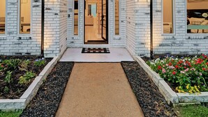 A modern house with a brick exterior, a large arched entrance, and a number "21318" displayed above the door. - Modern Farmhouse • Chef Kitchen • GameRoom • 77" OLED • BBQ Grill  (Katy)
