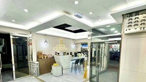 A hotel reception area with a marble floor, a reception desk, two chairs, and a glass door leading outside. - Hennessy Hotel (Hong Kong)